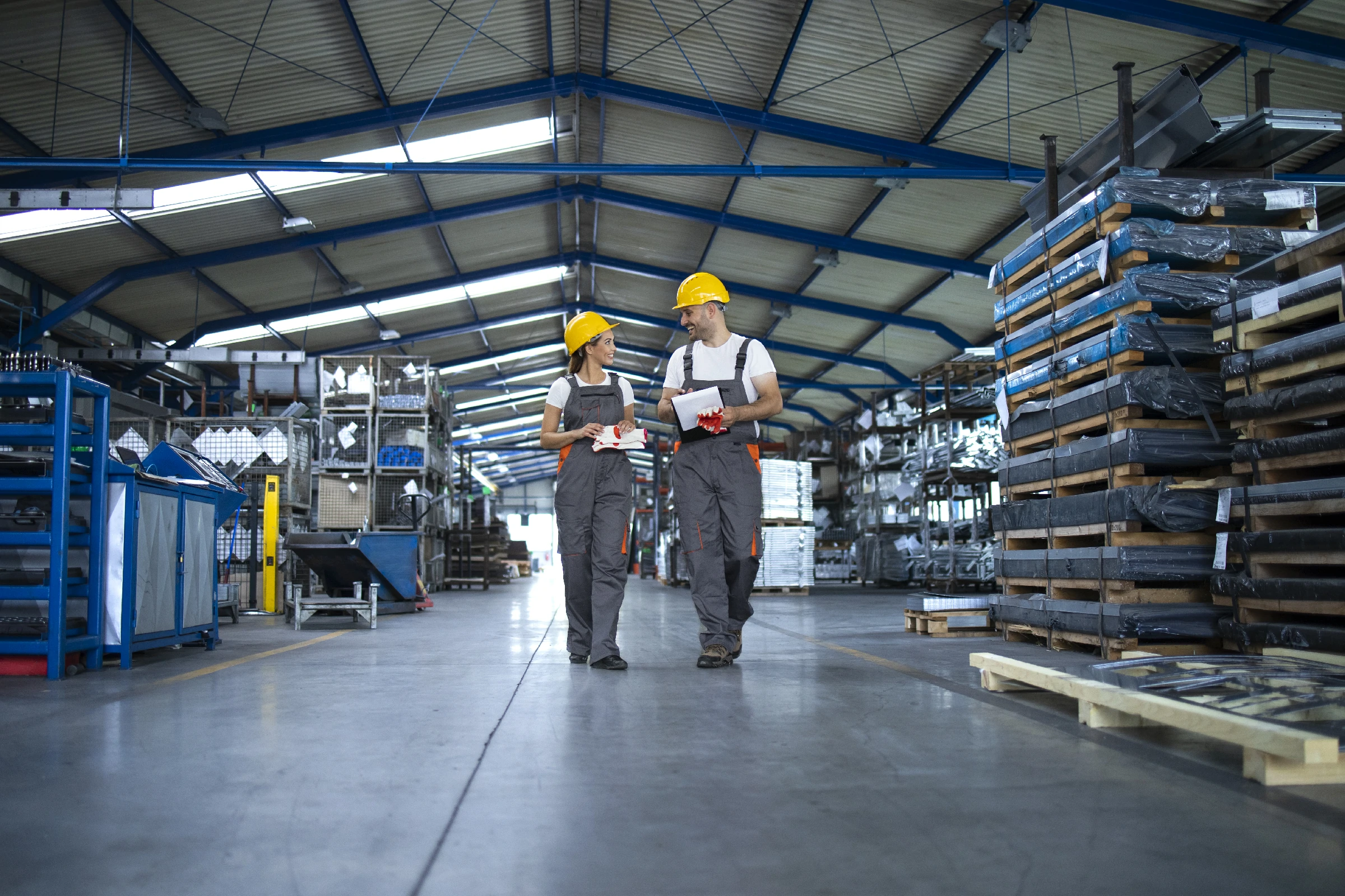 factory workers work wear yellow helmets walking through industrial production hall discussing about delivery deadline1